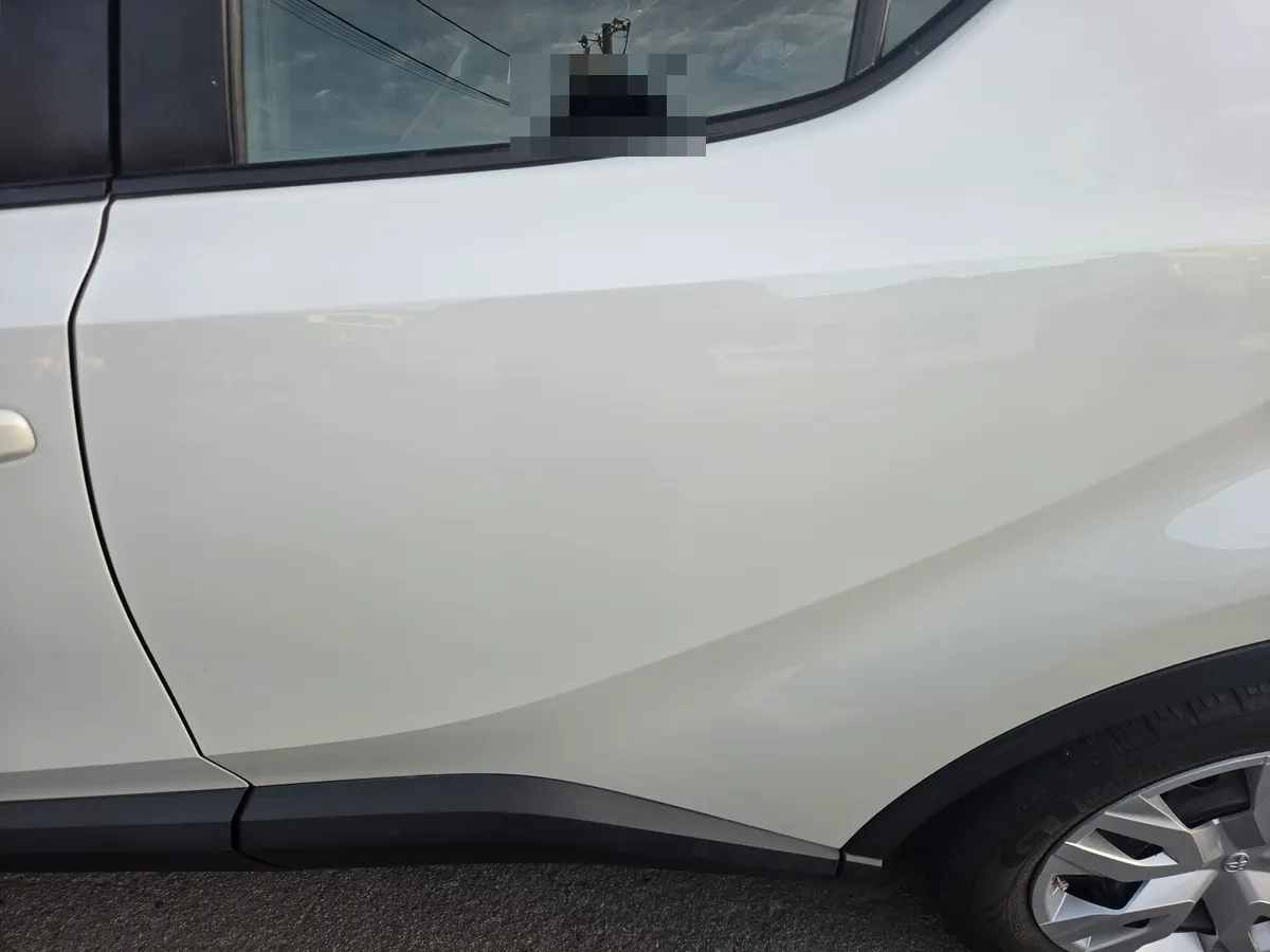 White Toyota C-HR rear passenger door after dent repair, paint refinishing, and window glass installation.
